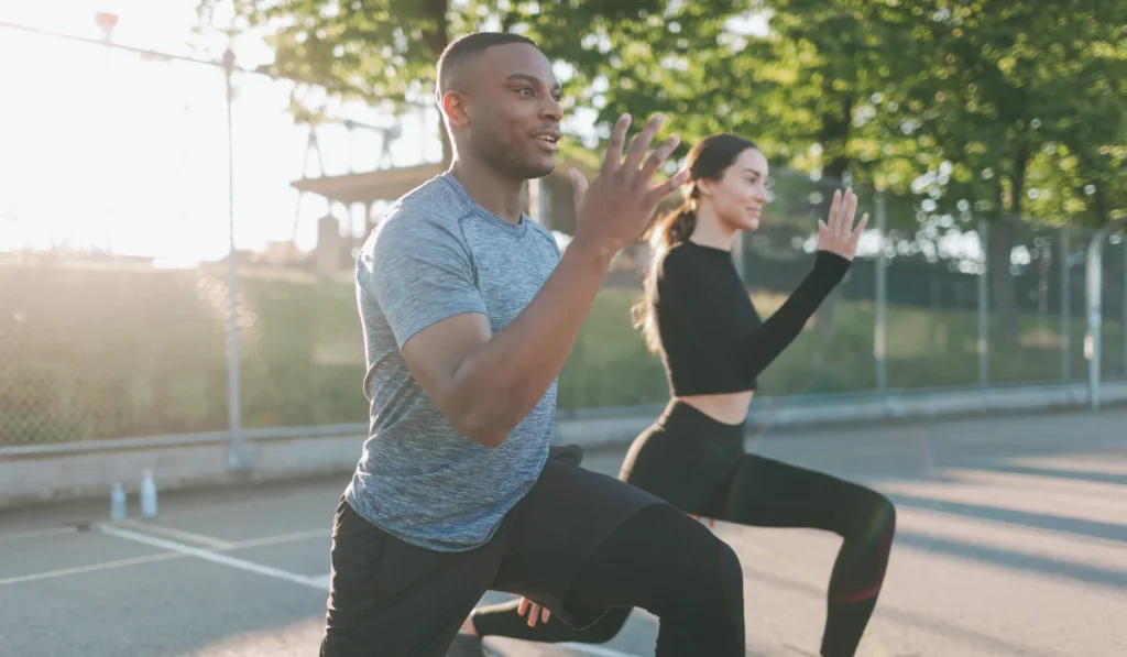 A young couple exercising in a parking lot on a bright sunny day.